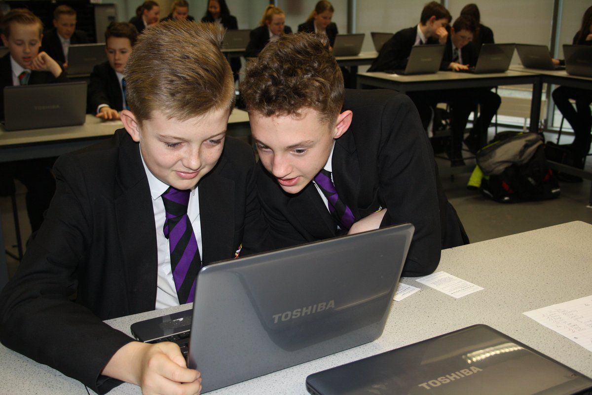 A photo of 2 students looking at a computer with the quote 